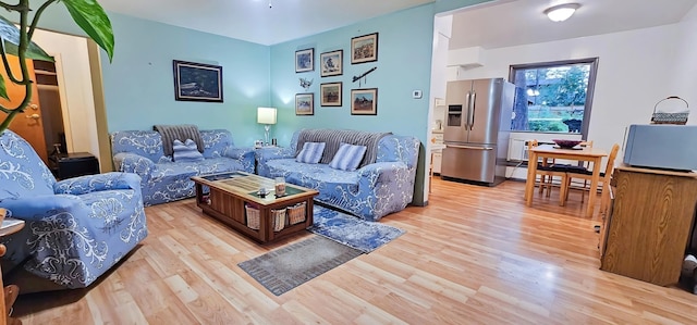 living room with a baseboard heating unit and light hardwood / wood-style flooring