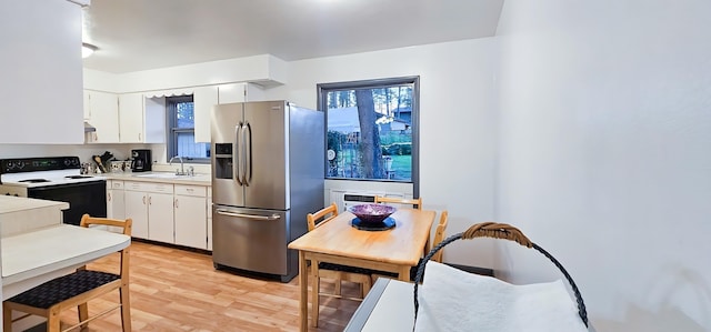 kitchen featuring sink, stainless steel fridge with ice dispenser, white cabinetry, light hardwood / wood-style floors, and white range with electric stovetop