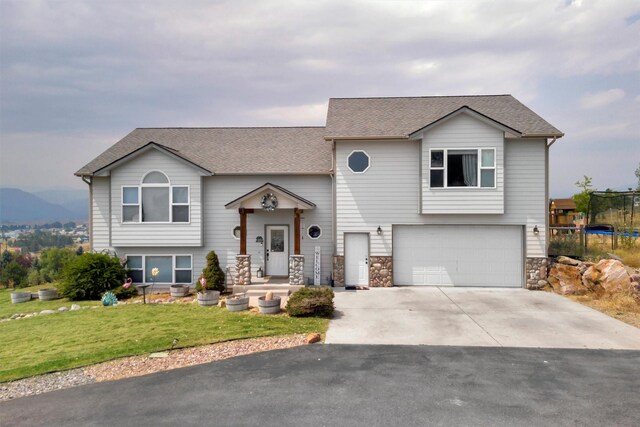 raised ranch featuring a garage and a trampoline