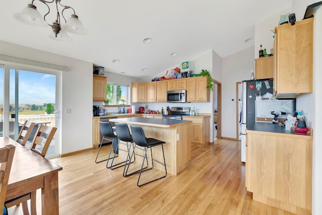 kitchen featuring lofted ceiling, a breakfast bar area, light hardwood / wood-style flooring, a center island, and appliances with stainless steel finishes