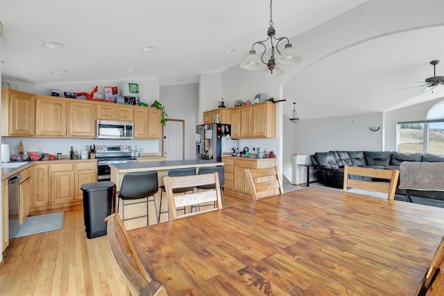 kitchen featuring appliances with stainless steel finishes, light hardwood / wood-style flooring, vaulted ceiling, light brown cabinets, and ceiling fan with notable chandelier