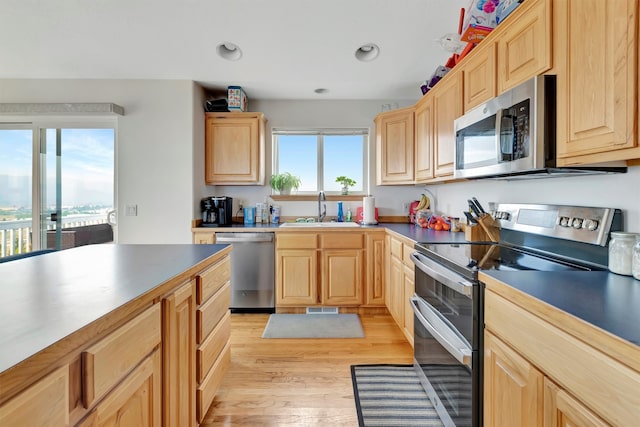 kitchen featuring stainless steel appliances, light brown cabinetry, light hardwood / wood-style flooring, and sink