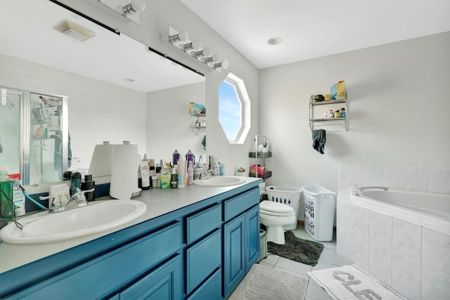 bathroom featuring double vanity, tile patterned flooring, tiled bath, and toilet