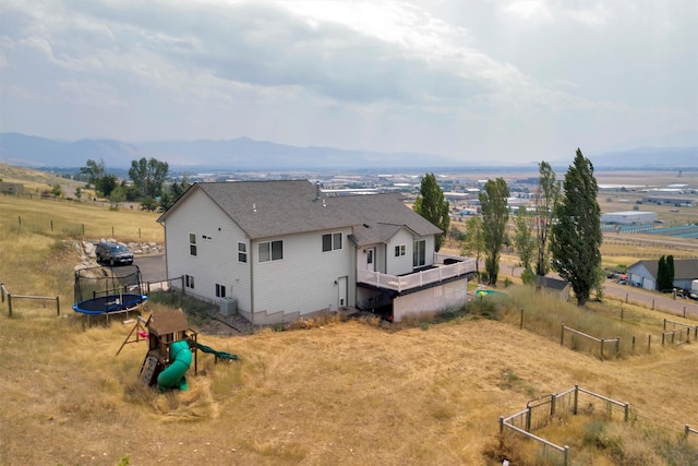 rear view of property featuring a trampoline, a mountain view, and a rural view