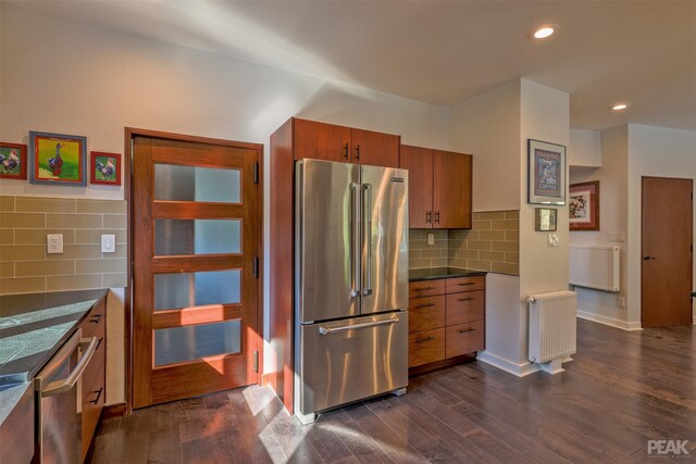 kitchen with radiator heating unit, high end fridge, dark hardwood / wood-style floors, and tasteful backsplash