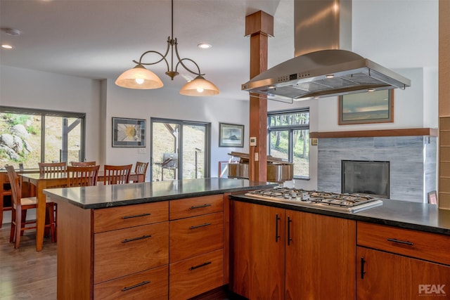 kitchen featuring tasteful backsplash, stainless steel gas stovetop, hanging light fixtures, island exhaust hood, and hardwood / wood-style flooring