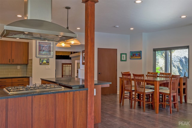 kitchen with pendant lighting, dark hardwood / wood-style floors, island exhaust hood, decorative backsplash, and stainless steel gas stovetop