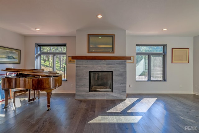 living room featuring dark wood-type flooring, a tile fireplace, and a wealth of natural light