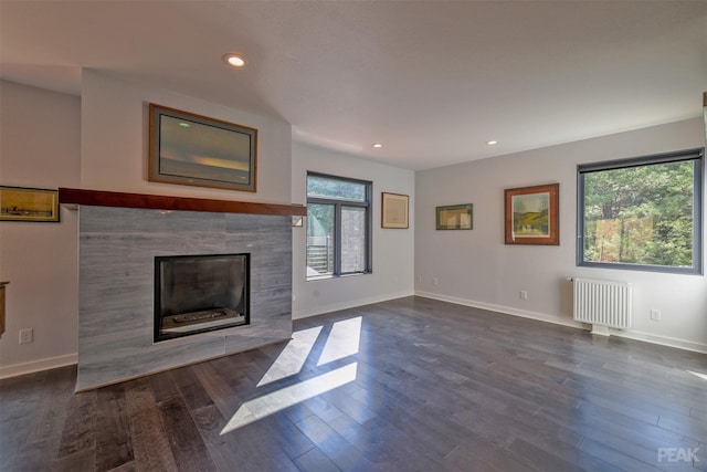 unfurnished living room with a fireplace, radiator heating unit, and dark hardwood / wood-style floors