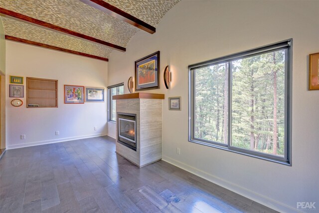 unfurnished living room with lofted ceiling with beams, dark hardwood / wood-style flooring, and a wealth of natural light