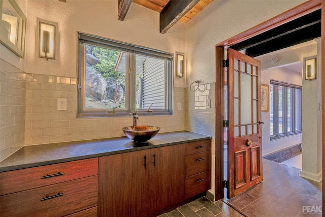 bathroom featuring tile patterned flooring, backsplash, beamed ceiling, and vanity