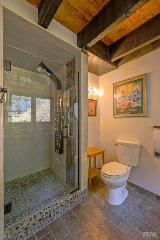 bathroom featuring a shower with door, toilet, and beamed ceiling