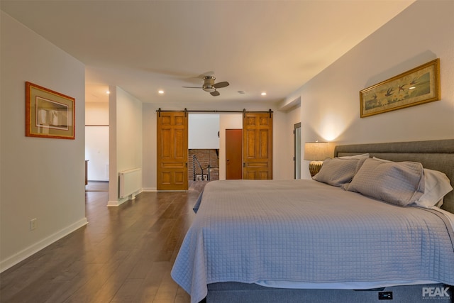 bedroom with radiator heating unit, a barn door, ceiling fan, and dark hardwood / wood-style floors