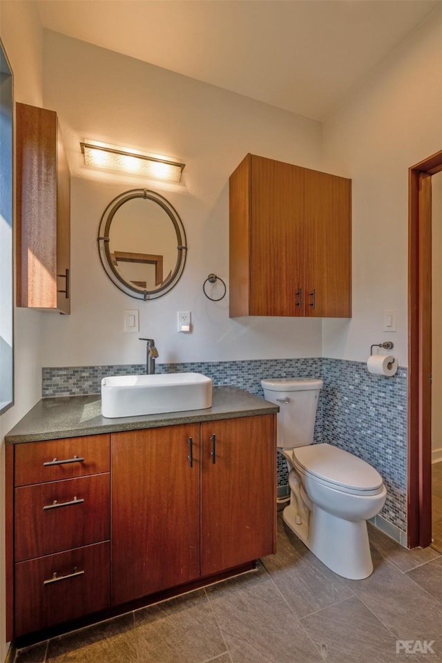 bathroom featuring vanity, toilet, and tile walls