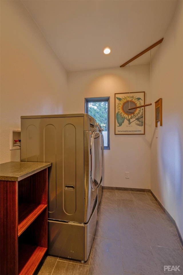 clothes washing area with light tile patterned flooring and washer and clothes dryer