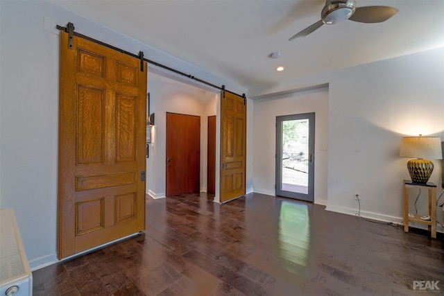 interior space featuring dark hardwood / wood-style flooring, ceiling fan, and a barn door