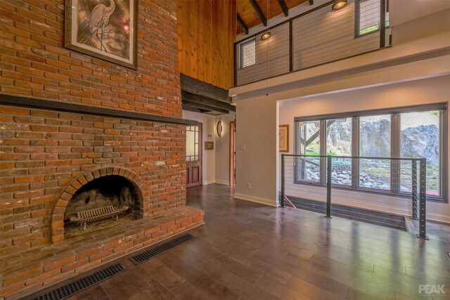 unfurnished living room featuring dark hardwood / wood-style floors, beamed ceiling, a fireplace, and high vaulted ceiling