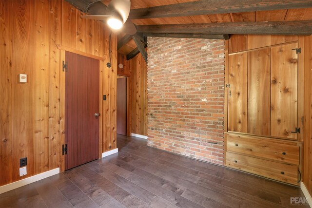 spare room featuring dark hardwood / wood-style flooring, lofted ceiling with beams, and wooden walls