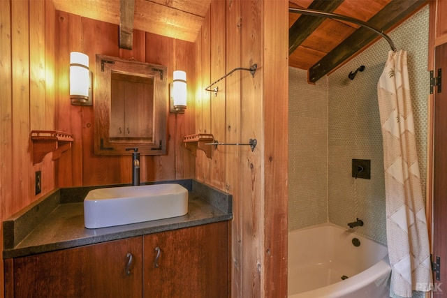 bathroom with beam ceiling, vanity, wooden walls, and shower / bath combo with shower curtain