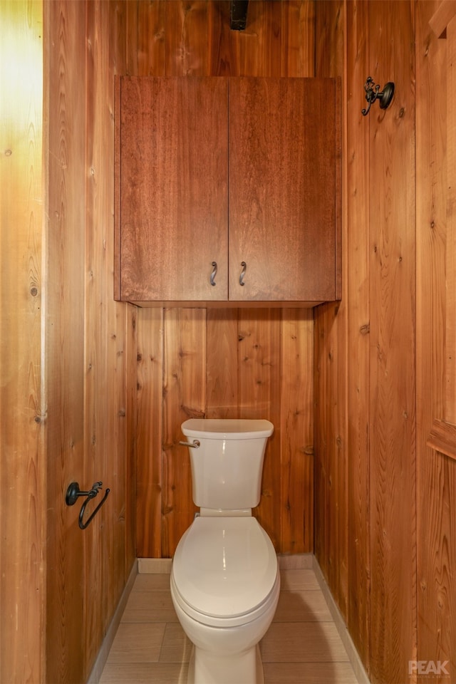 bathroom with wood walls and toilet