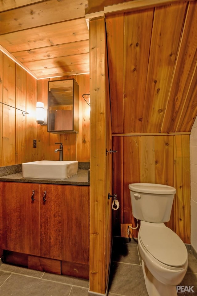 bathroom featuring toilet, wood walls, wooden ceiling, vanity, and tile patterned flooring