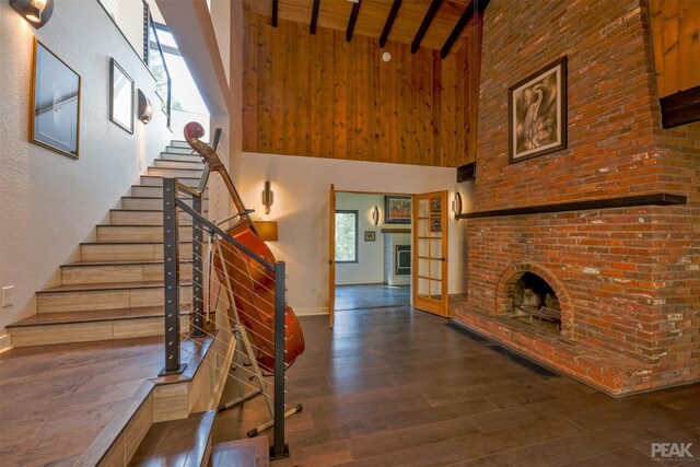 stairs with high vaulted ceiling, beam ceiling, dark hardwood / wood-style floors, and wood ceiling