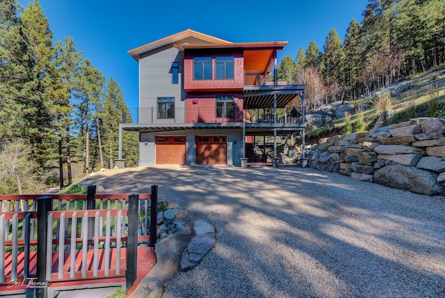 rear view of property with a wooden deck and a garage