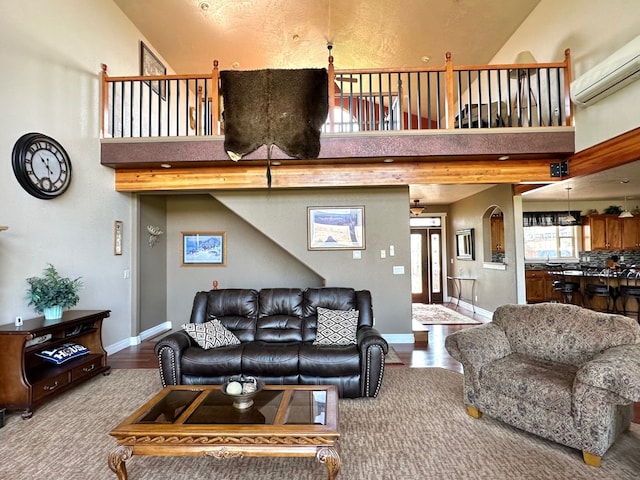 living room featuring a wall mounted air conditioner, a towering ceiling, and hardwood / wood-style floors