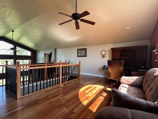 living room with a textured ceiling, a ceiling fan, baseboards, wood finished floors, and lofted ceiling