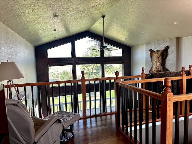 living area with a textured ceiling, ceiling fan, dark wood-type flooring, and vaulted ceiling