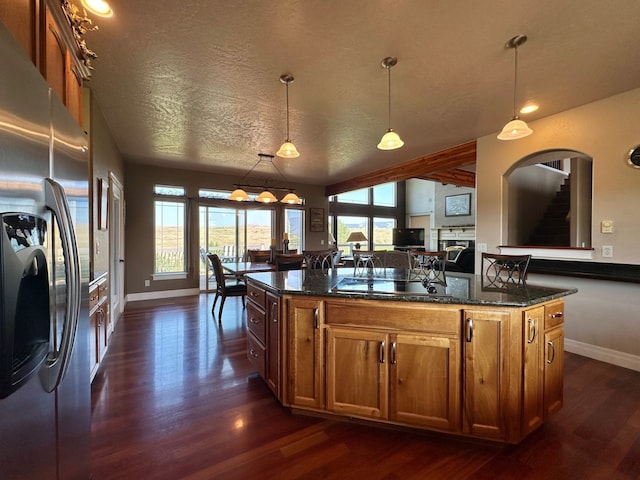 kitchen with stainless steel fridge with ice dispenser, dark hardwood / wood-style flooring, dark stone countertops, black gas stovetop, and decorative light fixtures