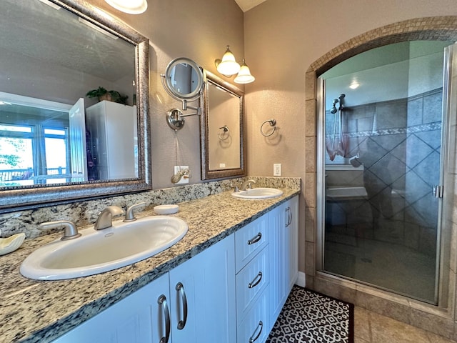 bathroom featuring a sink, tile patterned floors, a stall shower, and double vanity