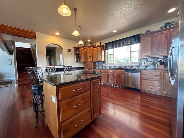 kitchen featuring a kitchen breakfast bar, arched walkways, open shelves, dark wood-style floors, and stainless steel appliances