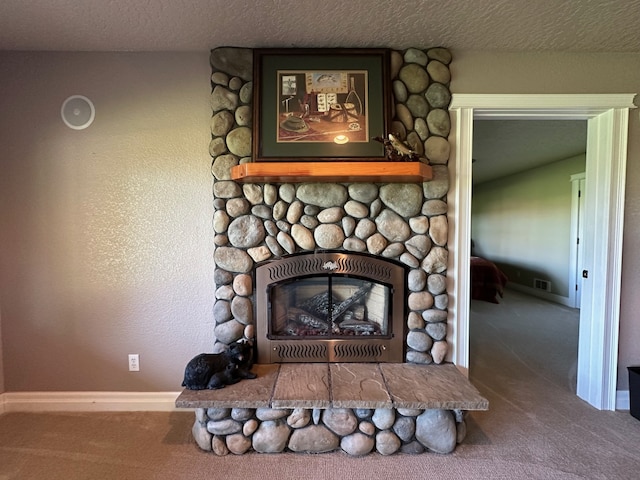 room details with a stone fireplace, carpet floors, and a textured ceiling