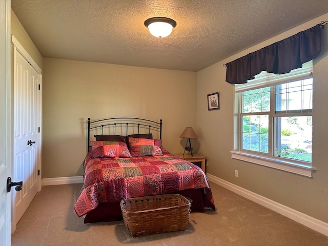 carpeted bedroom featuring a textured ceiling and baseboards