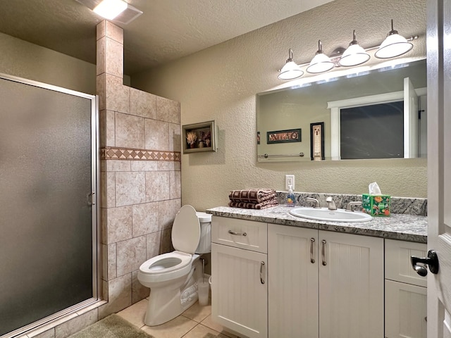 bathroom featuring vanity, tile patterned flooring, a textured wall, toilet, and a stall shower