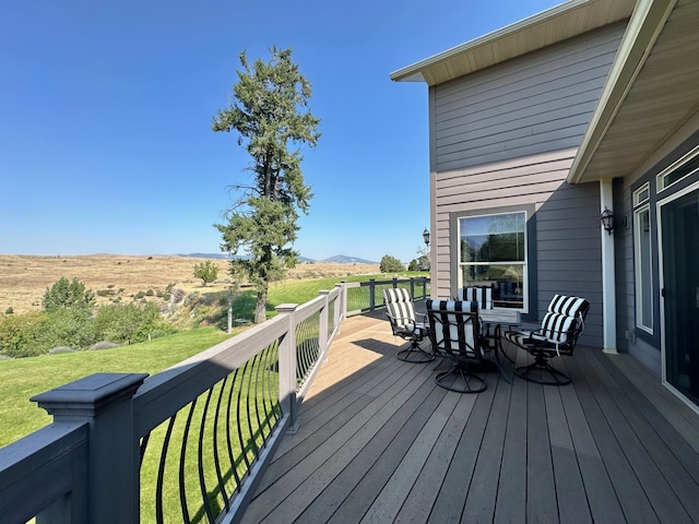 wooden terrace featuring a mountain view, a yard, and outdoor dining space