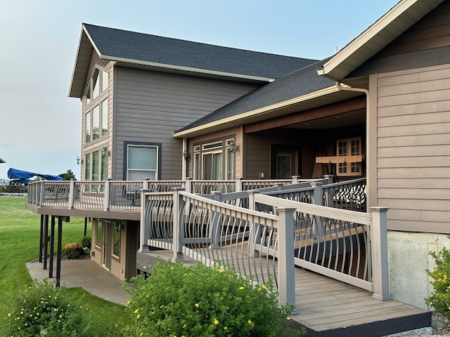 rear view of house with a yard, a wooden deck, and roof with shingles