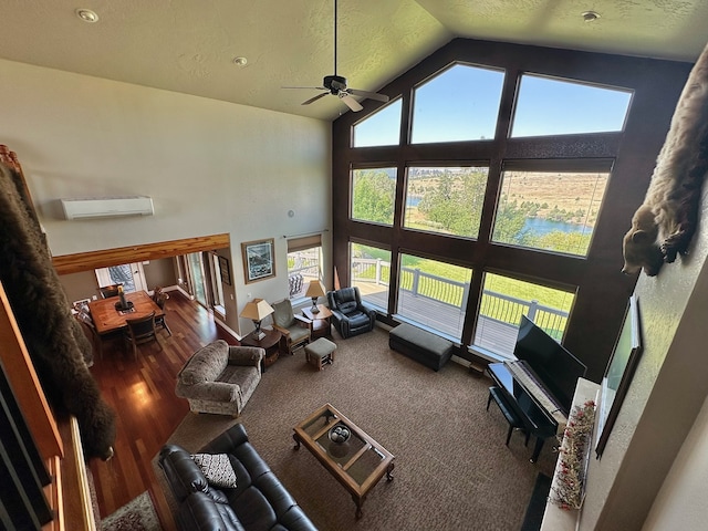 living room featuring high vaulted ceiling, ceiling fan, a textured ceiling, a wall mounted AC, and wood-type flooring