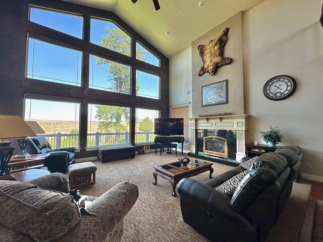 living area featuring a ceiling fan, a high end fireplace, high vaulted ceiling, baseboards, and carpet