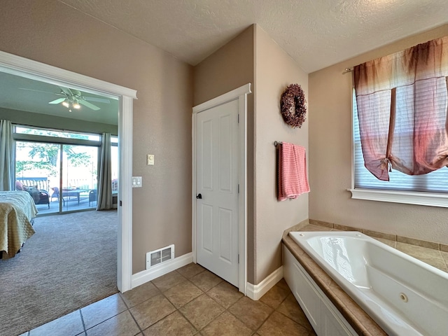 bathroom with a textured ceiling, tile patterned floors, a bathtub, and ceiling fan