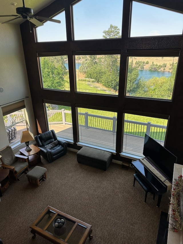 carpeted living room with ceiling fan and a high ceiling