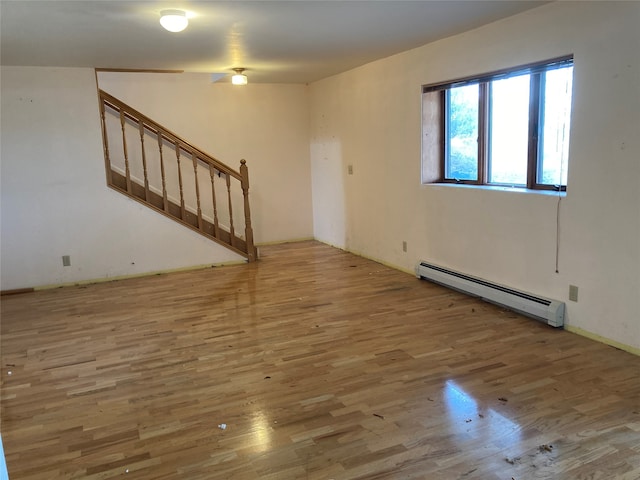 unfurnished room featuring a baseboard heating unit and hardwood / wood-style flooring