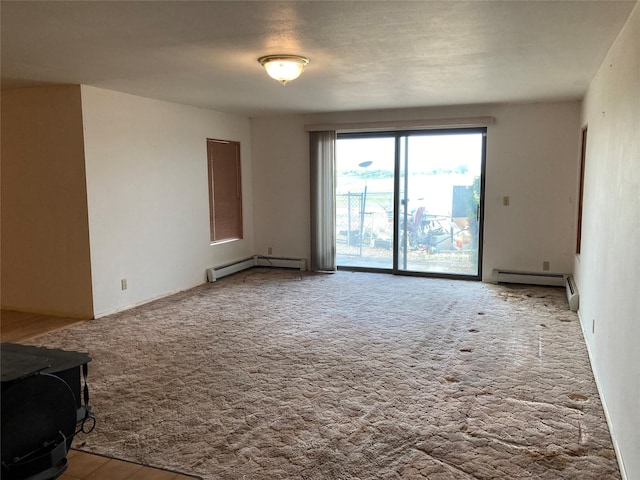 384 Eagle Ln, Corvallis, MT 59828 - carpeted spare room featuring a baseboard radiator and a wood stove