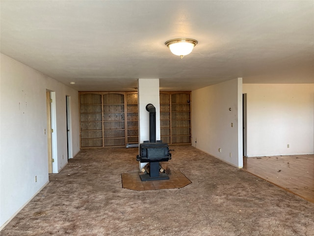 unfurnished living room with a wood stove and carpet floors