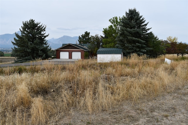 view of yard featuring a mountain view, a shed, a rural view, and a garage