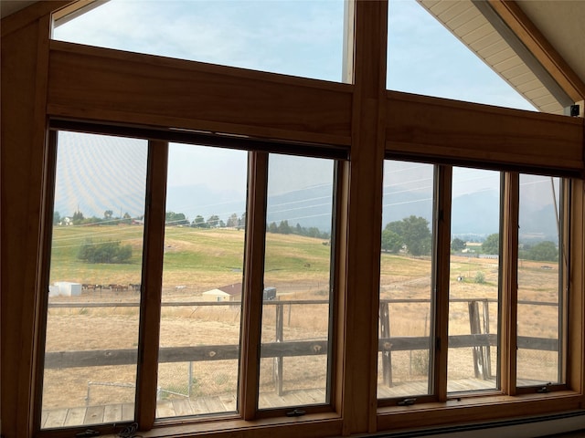 doorway to outside with a healthy amount of sunlight, vaulted ceiling, and a rural view