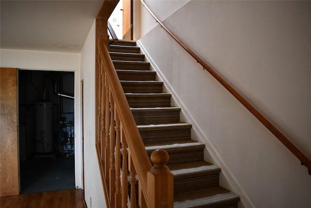 stairs featuring wood-type flooring and gas water heater