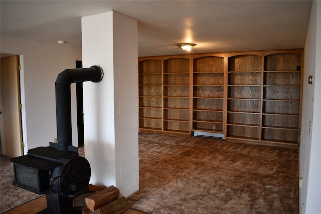 interior space featuring a wood stove, a baseboard heating unit, and dark carpet