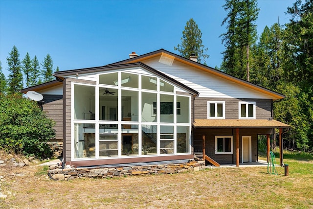 rear view of house featuring a sunroom, a lawn, a chimney, and a patio